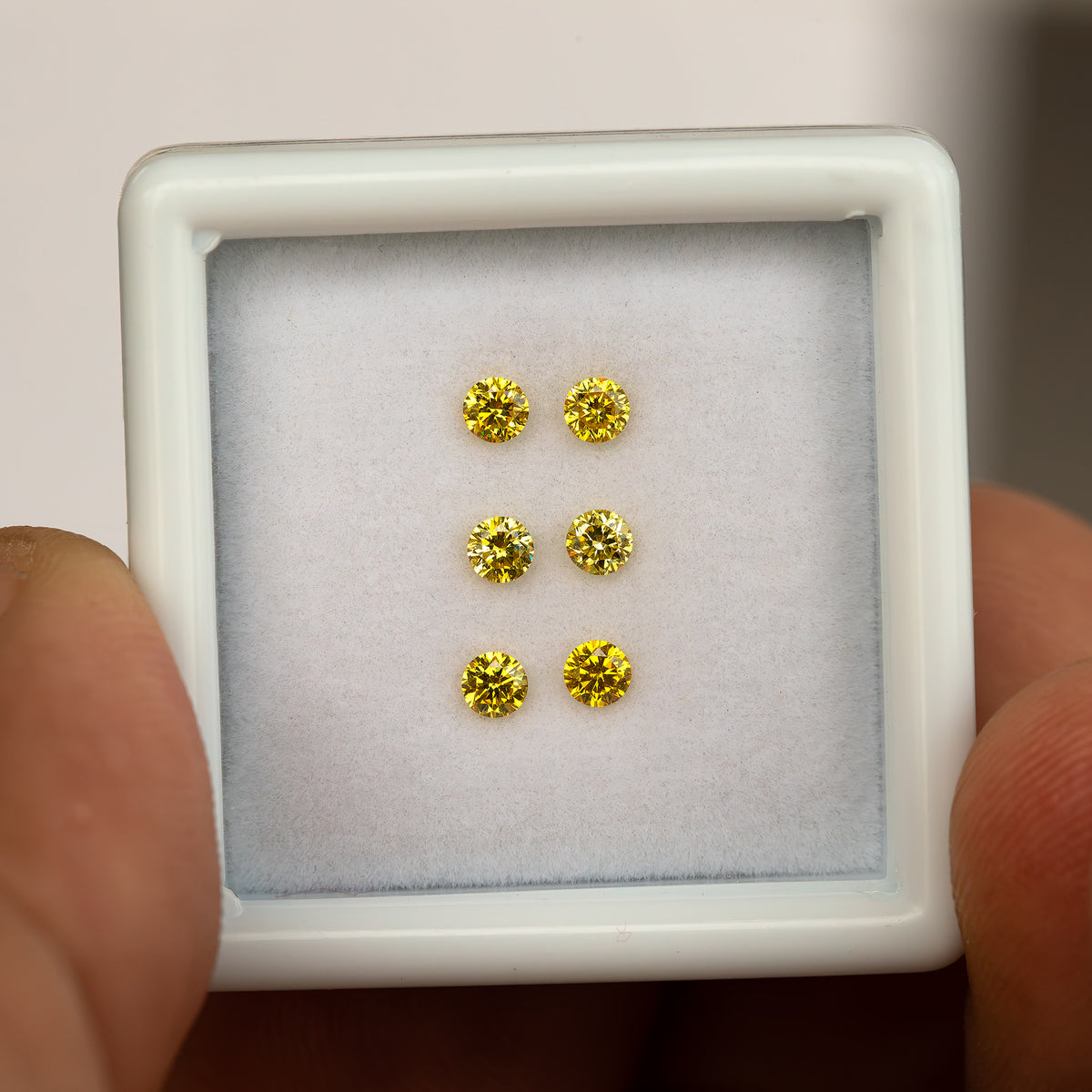 Closer front view of a hand-held white tray showing three yellow diamond pairs.