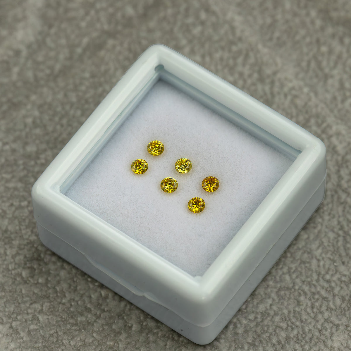 Low angled white tray containing three yellow diamond pairs on a grey surface.