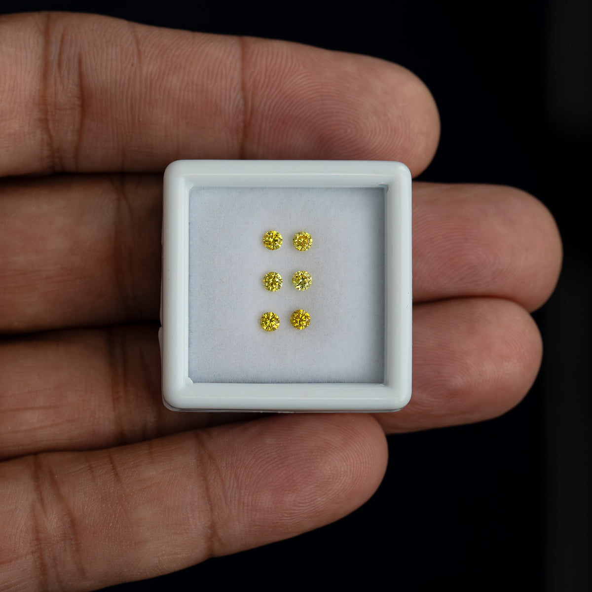 White tray with three yellow diamond pairs resting on a palm for scale.