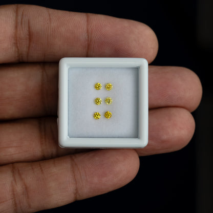 White tray with three yellow diamond pairs resting on a palm for scale.