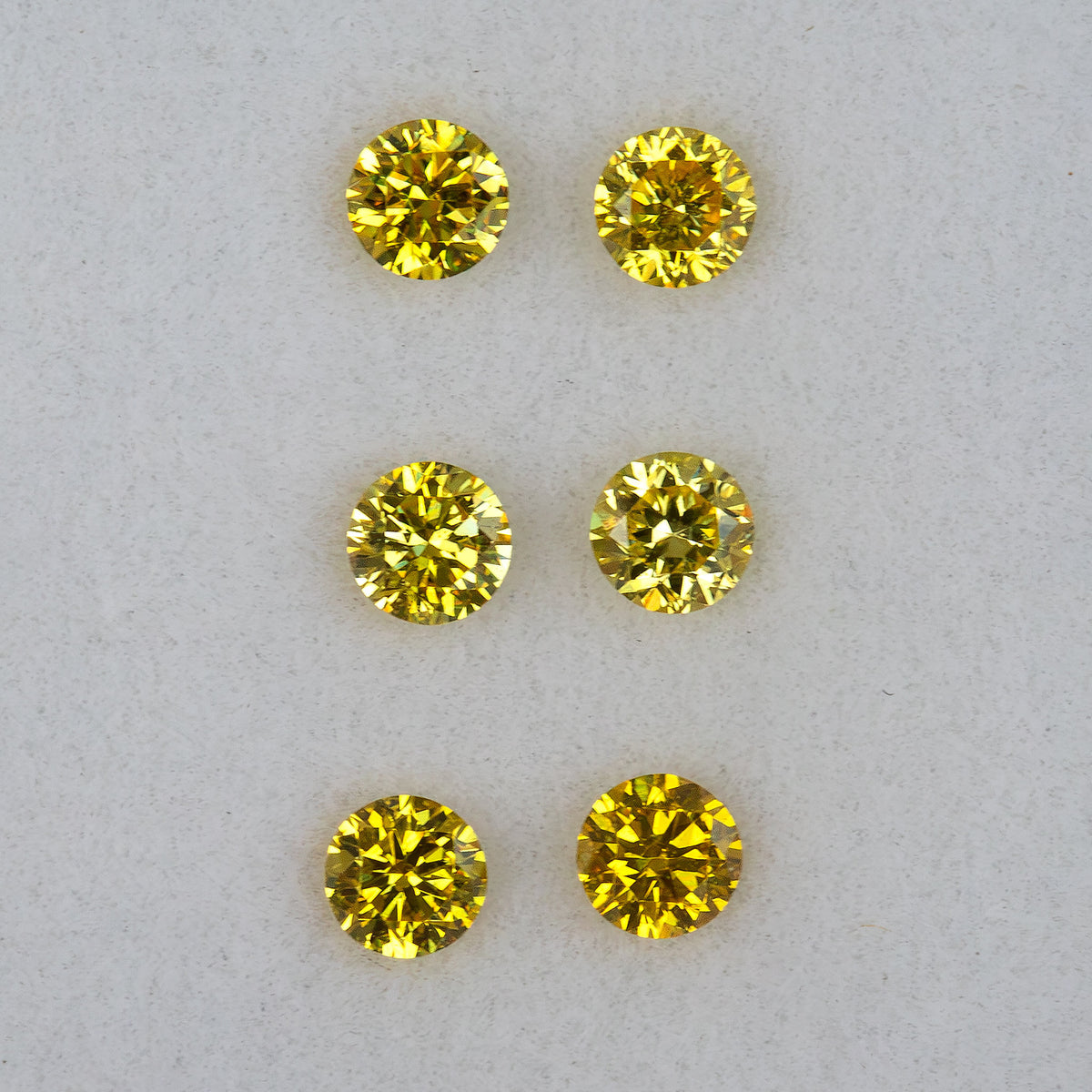 Crisp face-up view of three round brilliant yellow diamond pairs in rows.