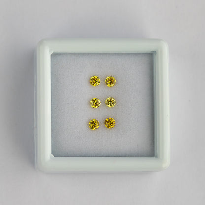 Wide view of the three yellow diamond pairs in a white tray on a pale surface.