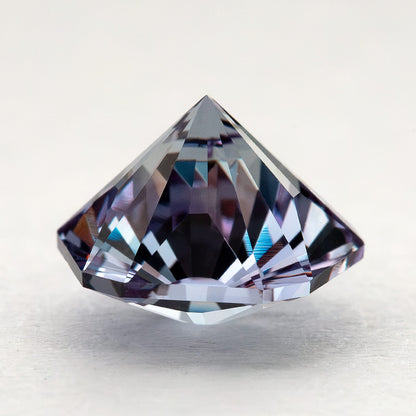 Pointed pavilion and side facets of the pentagon lab-grown sapphire resting on a pale surface.