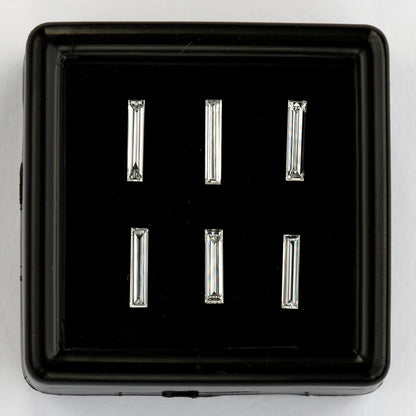 Front view of six baguette diamond options in a black box on a pale background, showing the differing widths and bright longitudinal facets.