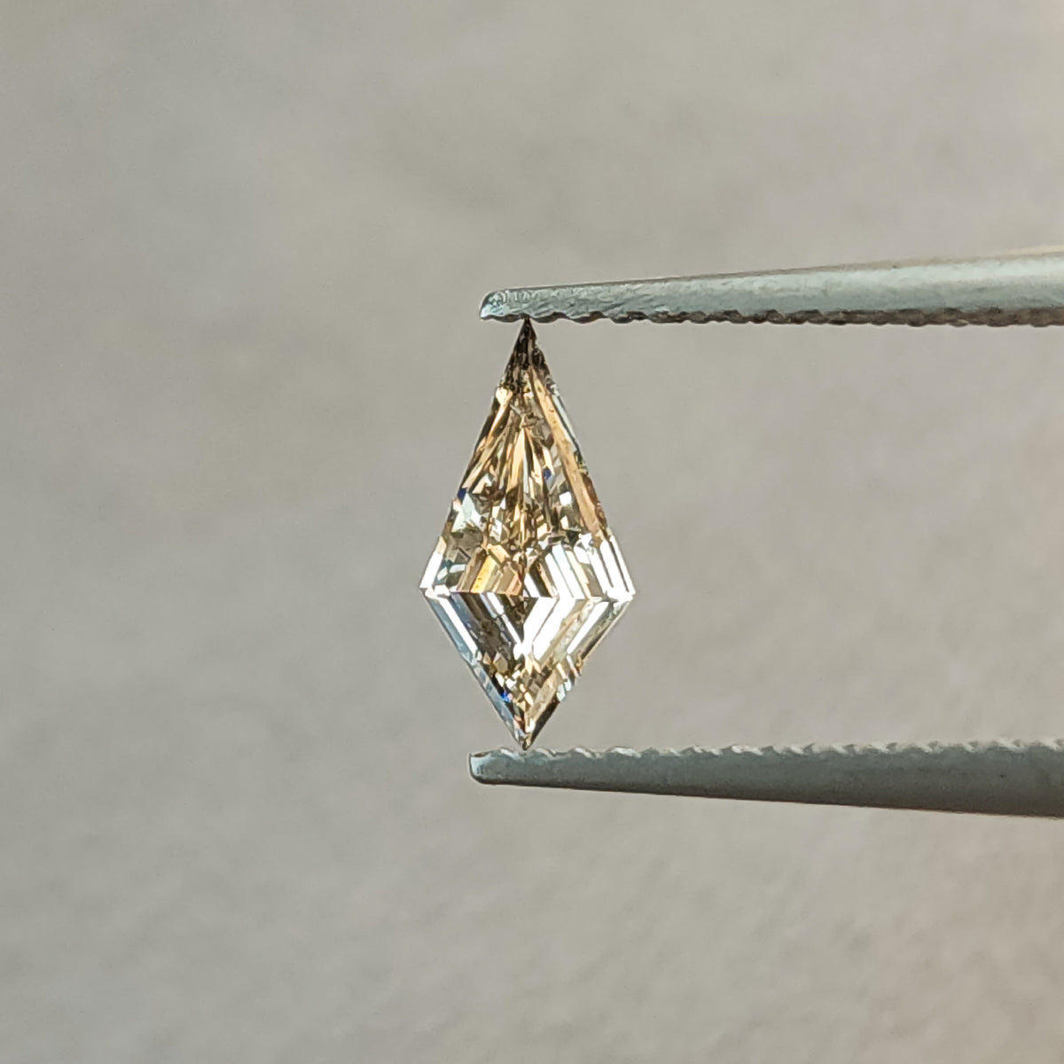 Alternate face-up angle of the elongated kite lab-grown diamond, showing warmer champagne reflections and its long two-pointed outline.
