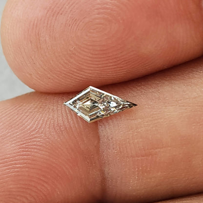 The 0.39 carat elongated kite lab-grown diamond resting on fingertips, showing its 9.47 × 4.58 mm face-up size.