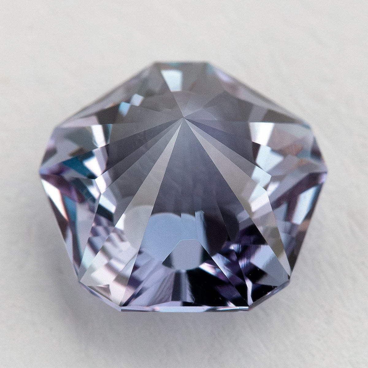 Reverse view of the pentagon sapphire, showing broad pavilion facets rather than its radial face-up pattern.