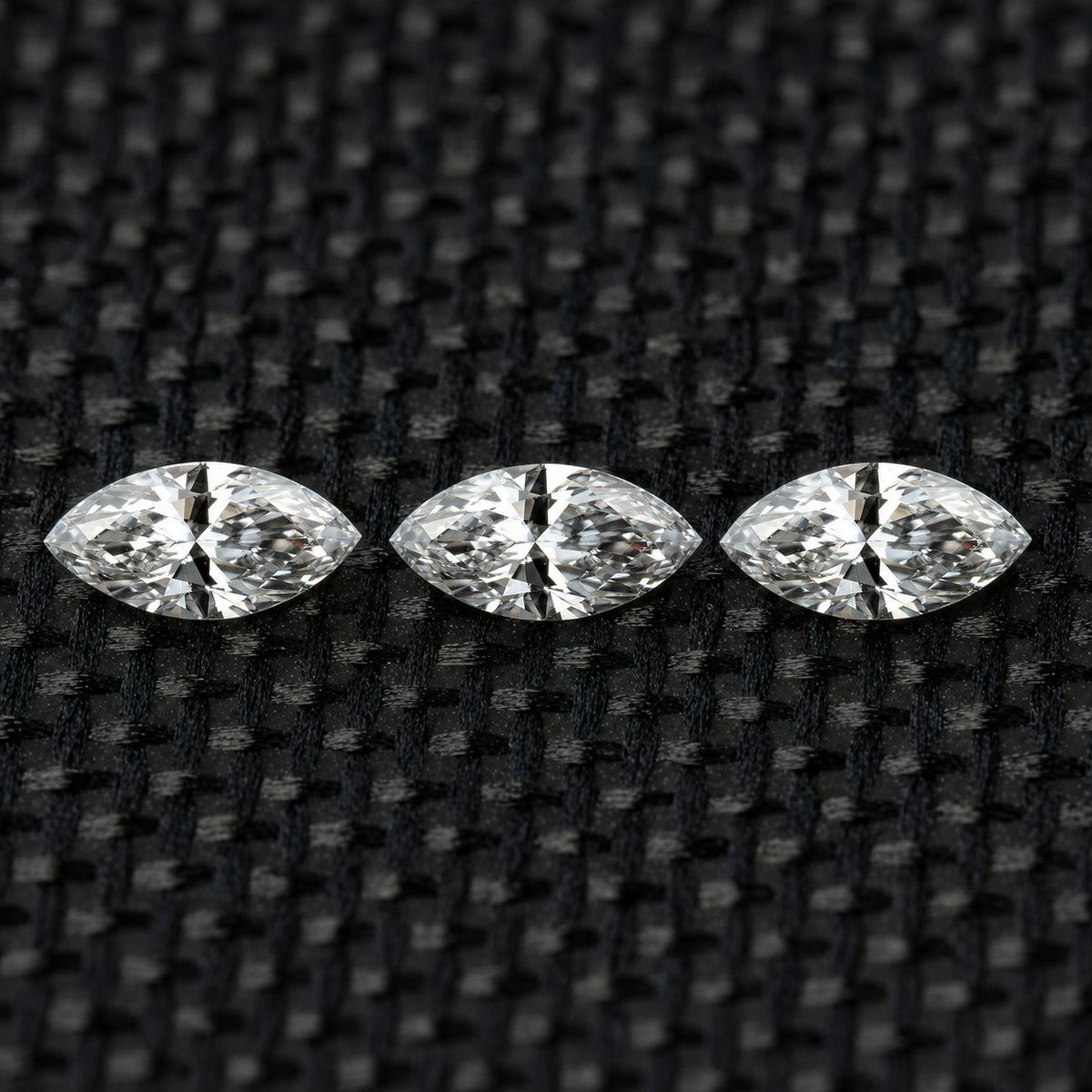 Three face-up marquise diamonds in a horizontal row on black fabric, illustrating the three-piece selection.