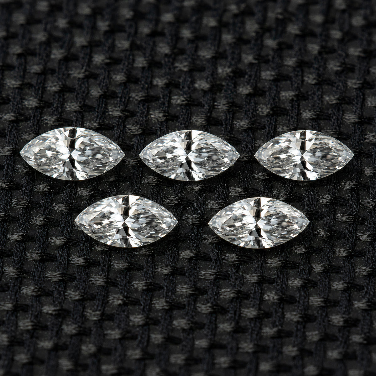 Five face-up marquise diamonds in two rows on black fabric, illustrating the five-piece selection.