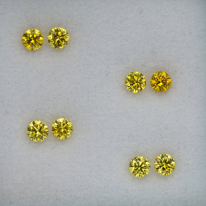 Macro view of the four round brilliant yellow diamond pairs arranged diagonally.