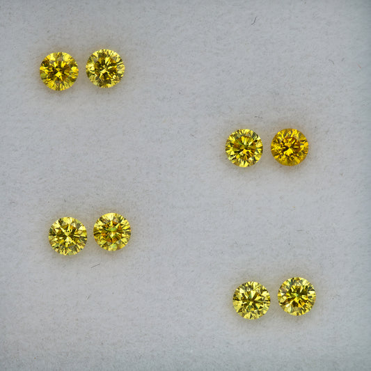 Macro view of the four round brilliant yellow diamond pairs arranged diagonally.