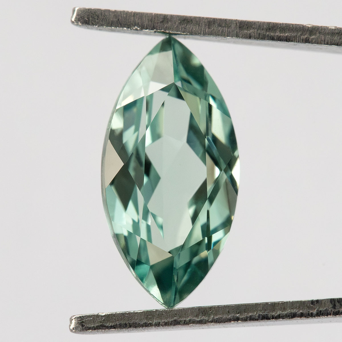 Face-up view of a mint-green marquise lab-grown sapphire held vertically between tweezers.

Video of a mint-green marquise lab-grown sapphire shown against fingers.