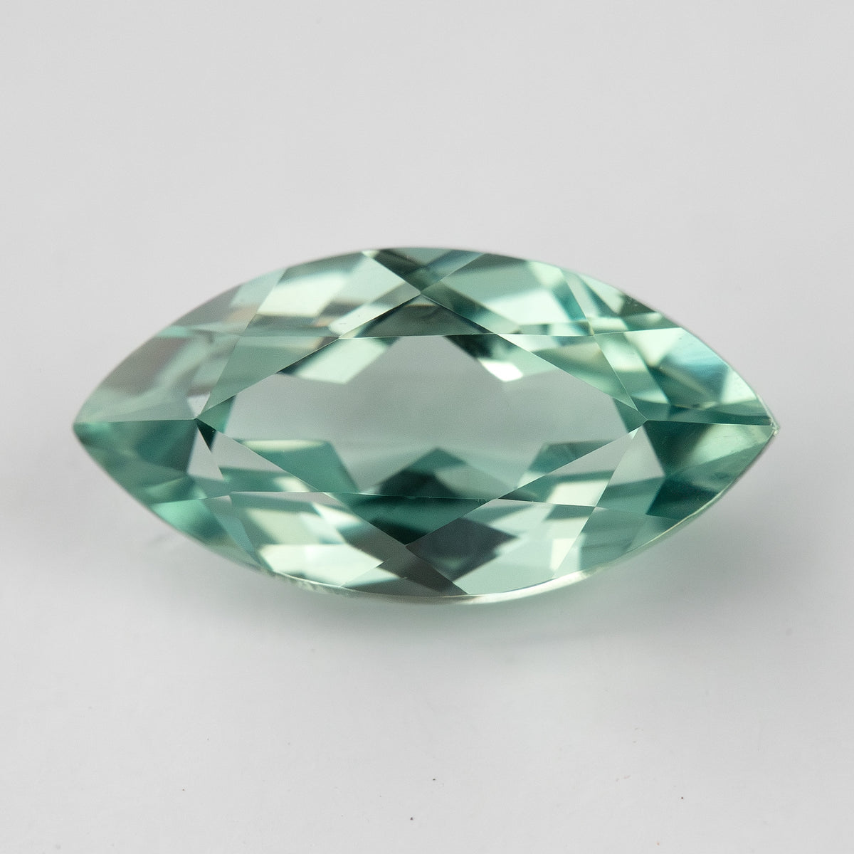 Horizontal face-up view of a mint-green marquise lab-grown sapphire, showing a pattern of light and dark facets.