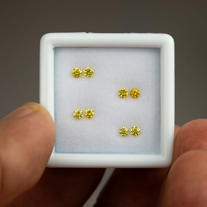 White tray of four yellow diamond pairs held at a slight angle by fingers.