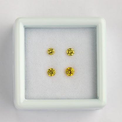 Overhead view of four yellow diamonds in two rows inside a white tray.