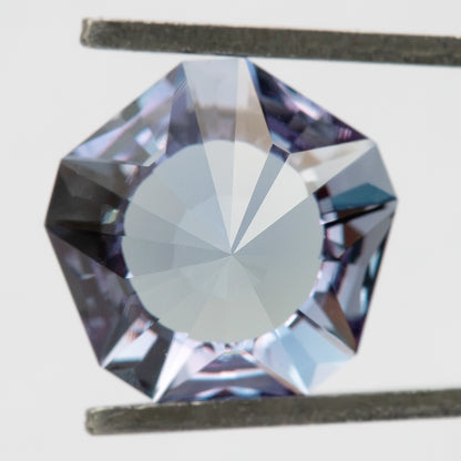 Pavilion-facing view of the lab-grown sapphire held in tweezers, showing a broad central reverse facet.