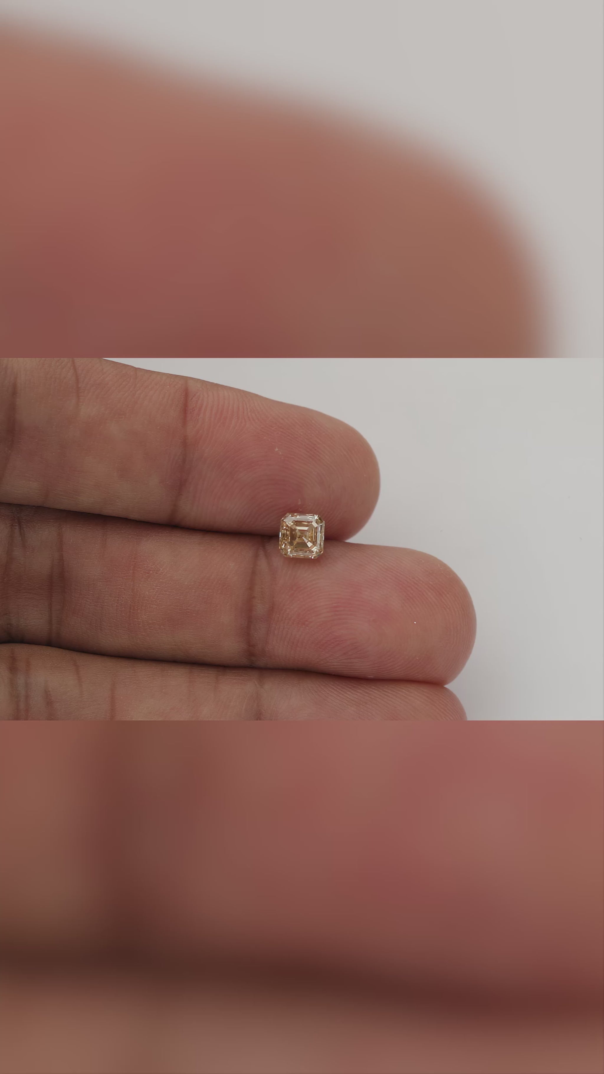 Champagne Asscher-cut natural diamond shown face-up on fingers at changing scales, with visible dark clarity characteristics.