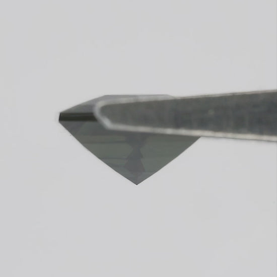 Natural-light video of the exact BNS205 sapphire tilting in tweezers and between fingers, showing changing reflections and scale.