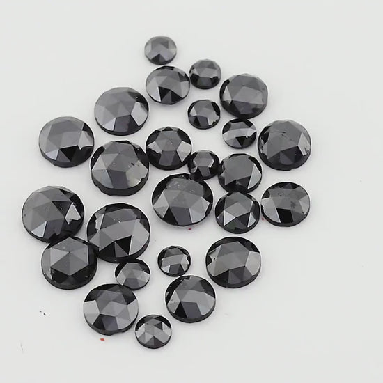 Moving views of a black round rose-cut diamond parcel, showing mixed sizes and facet reflections.