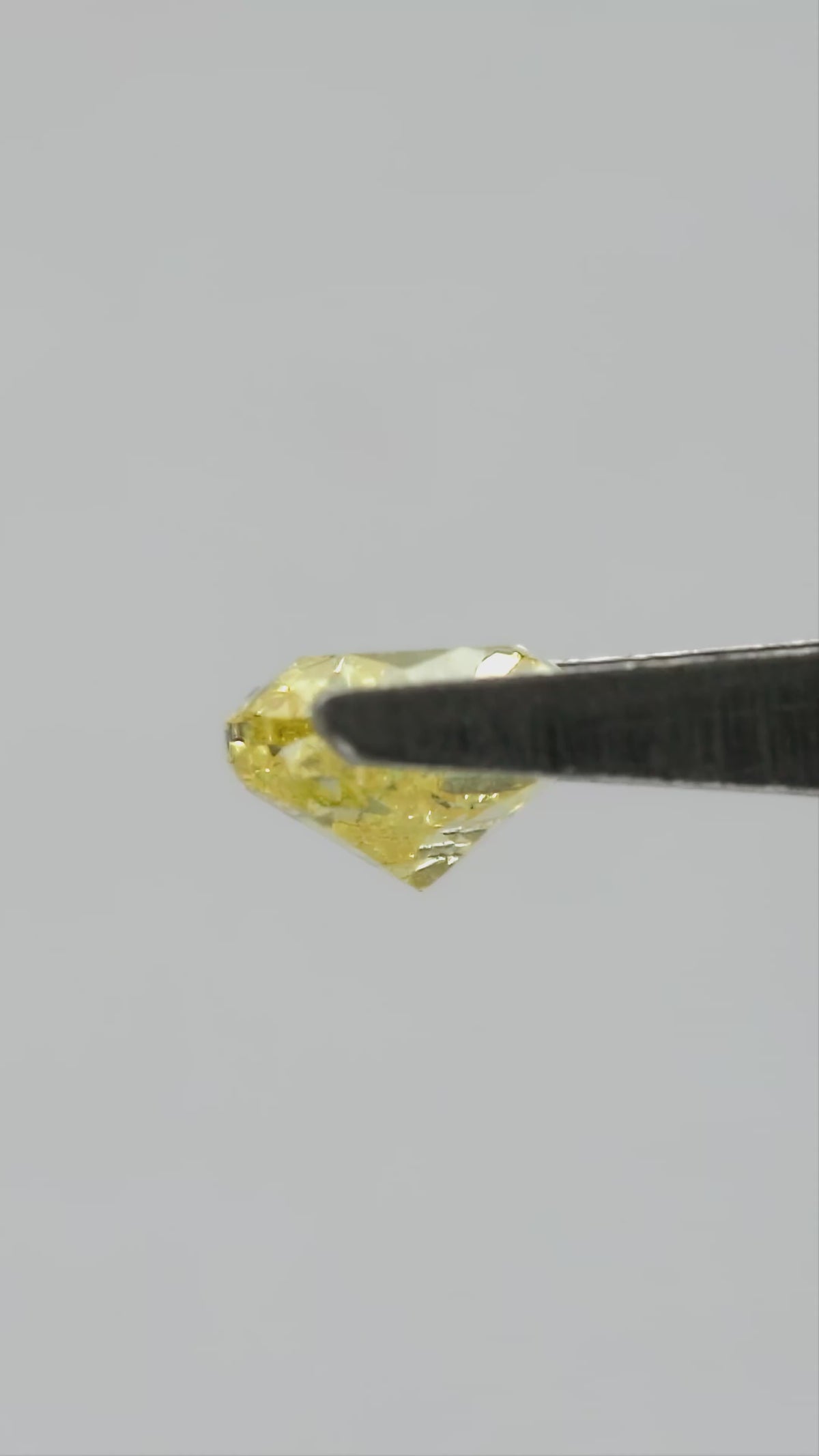 Yellow heart-shaped diamond rotating in tweezers, followed by fingertip views for scale.