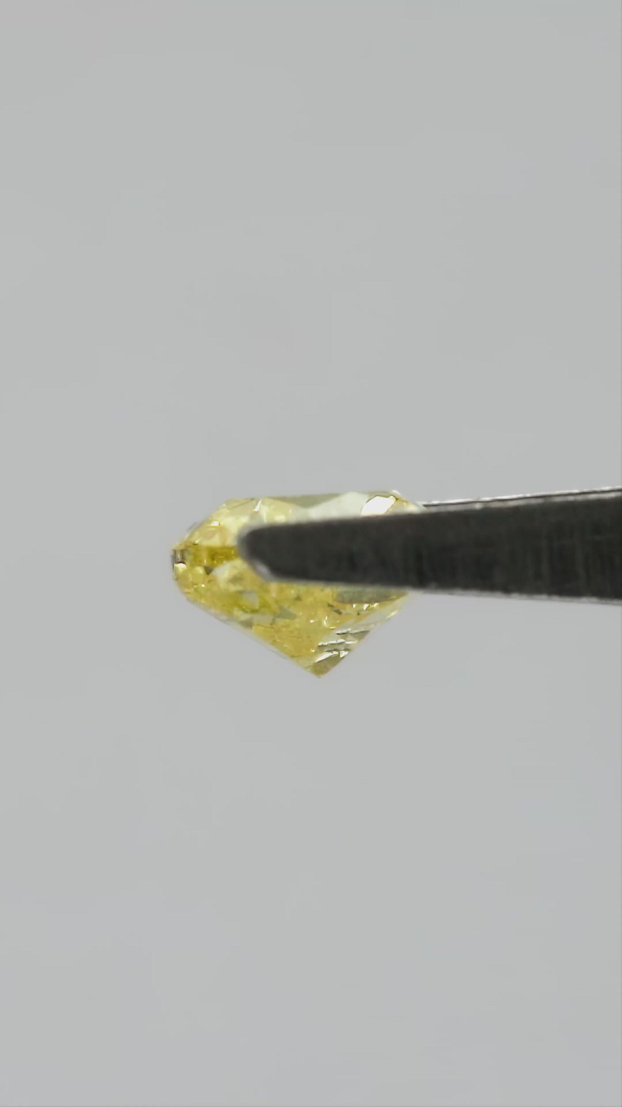 Yellow heart-shaped diamond rotating in tweezers, followed by fingertip views for scale.