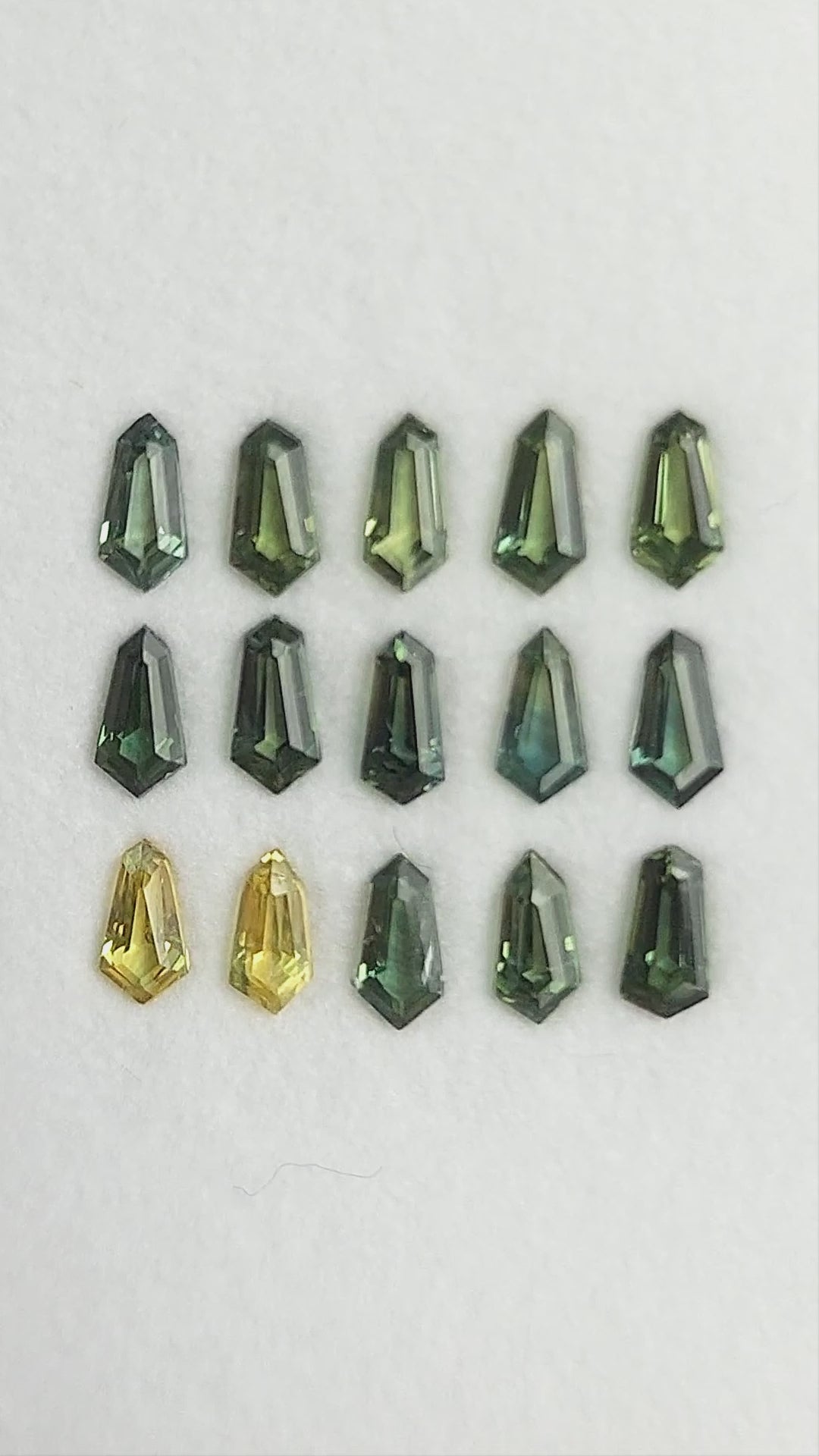 Green and yellow-green sapphire selection shown in rotating views of the fifteen-stone tray; sold one selected stone at a time.