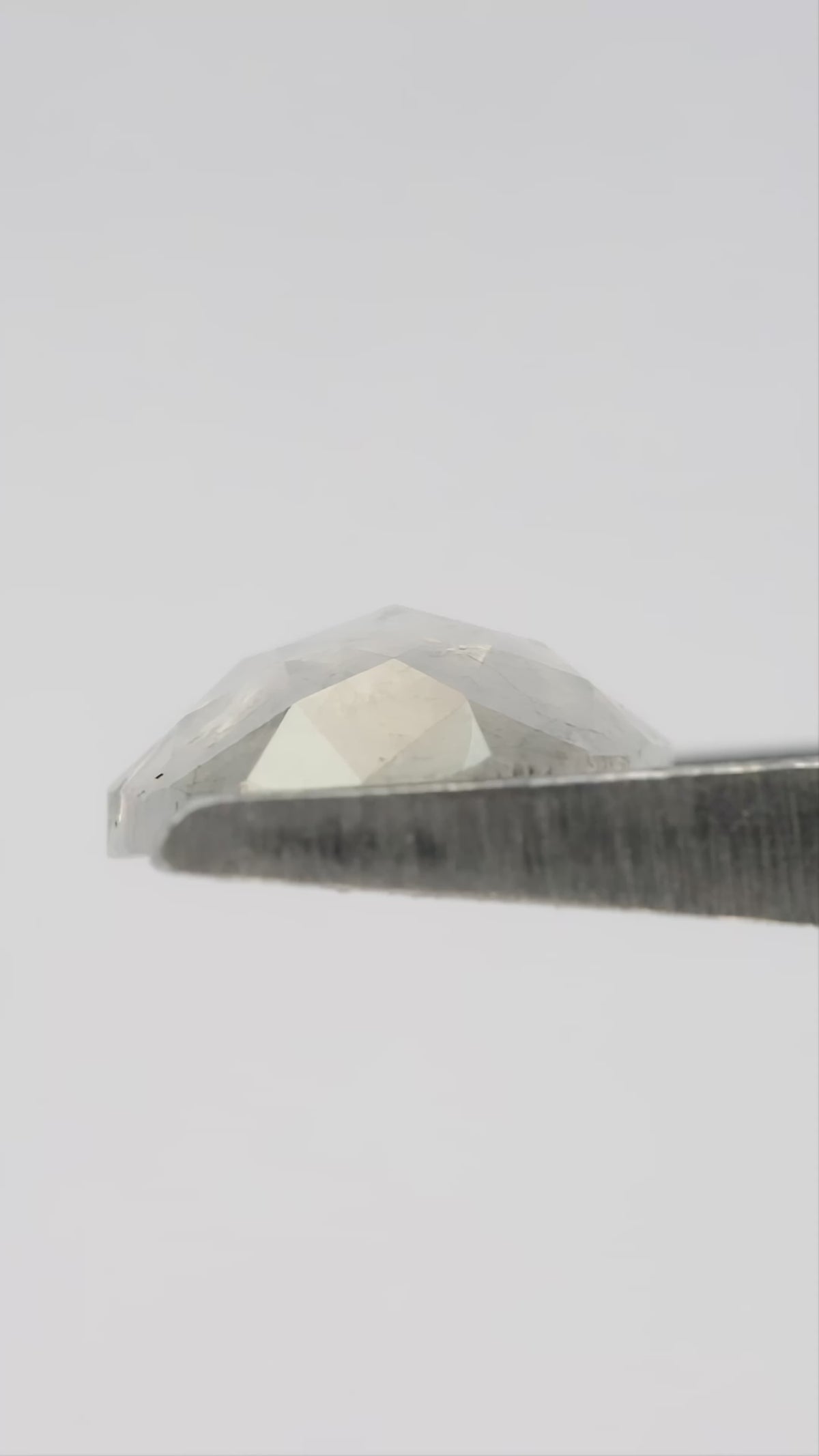 Finished video of the oval diamond rotating in metal tweezers, followed by fingertip scale, taken in natural light.