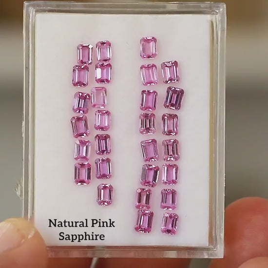 Hand-held tray containing the representative pink emerald-cut sapphire parcel, shown at slightly different angles; purchase is for one random stone.