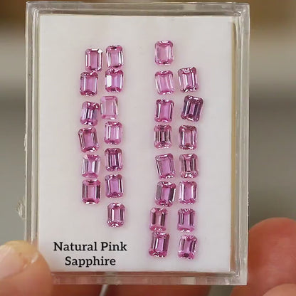 Hand-held tray containing the representative pink emerald-cut sapphire parcel, shown at slightly different angles; purchase is for one random stone.