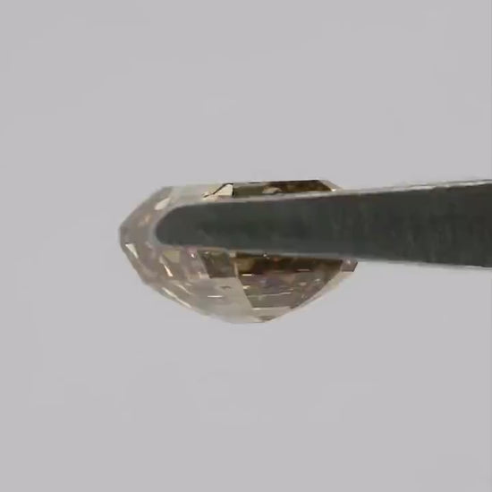 Natural-daylight tweezers video of the exact 1.01 ct natural fancy brownish-yellow emerald cut diamond rotating through face-up, tilted and profile views, then shown on a fingertip for scale.