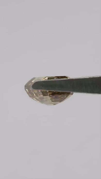 Natural-daylight tweezers video of the exact 1.01 ct natural fancy brownish-yellow emerald cut diamond rotating through face-up, tilted and profile views, then shown on a fingertip for scale.