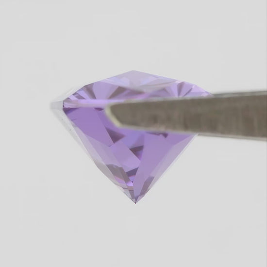Representative violet lab-grown sapphire rotating in tweezers, with face-up and finger-scale views.