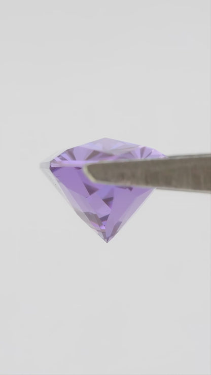 Representative violet lab-grown sapphire rotating in tweezers, with face-up and finger-scale views.