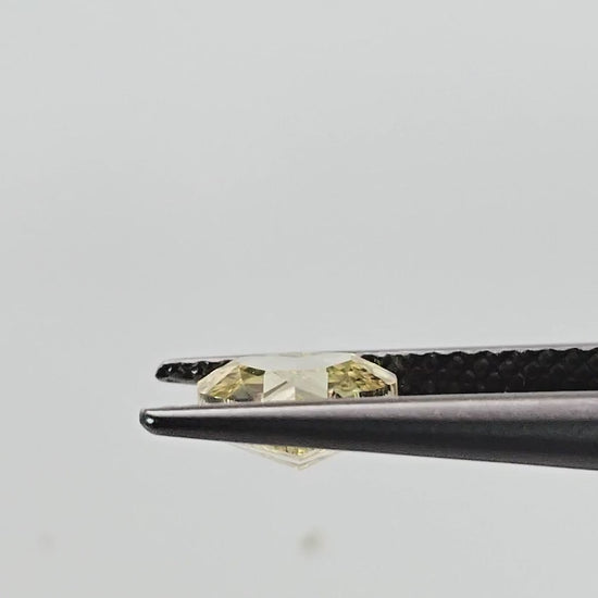 Yellow heart diamond turning in tweezers and shown on fingertips for scale.