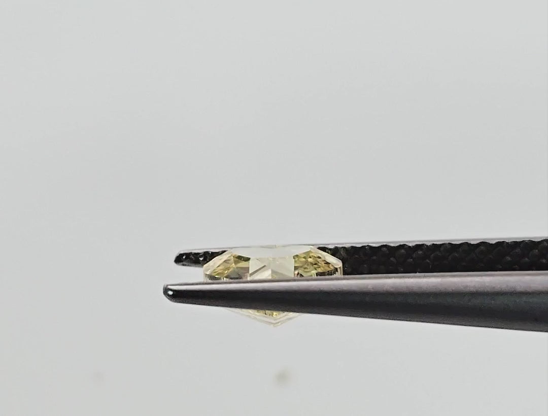 Yellow heart diamond turning in tweezers and shown on fingertips for scale.