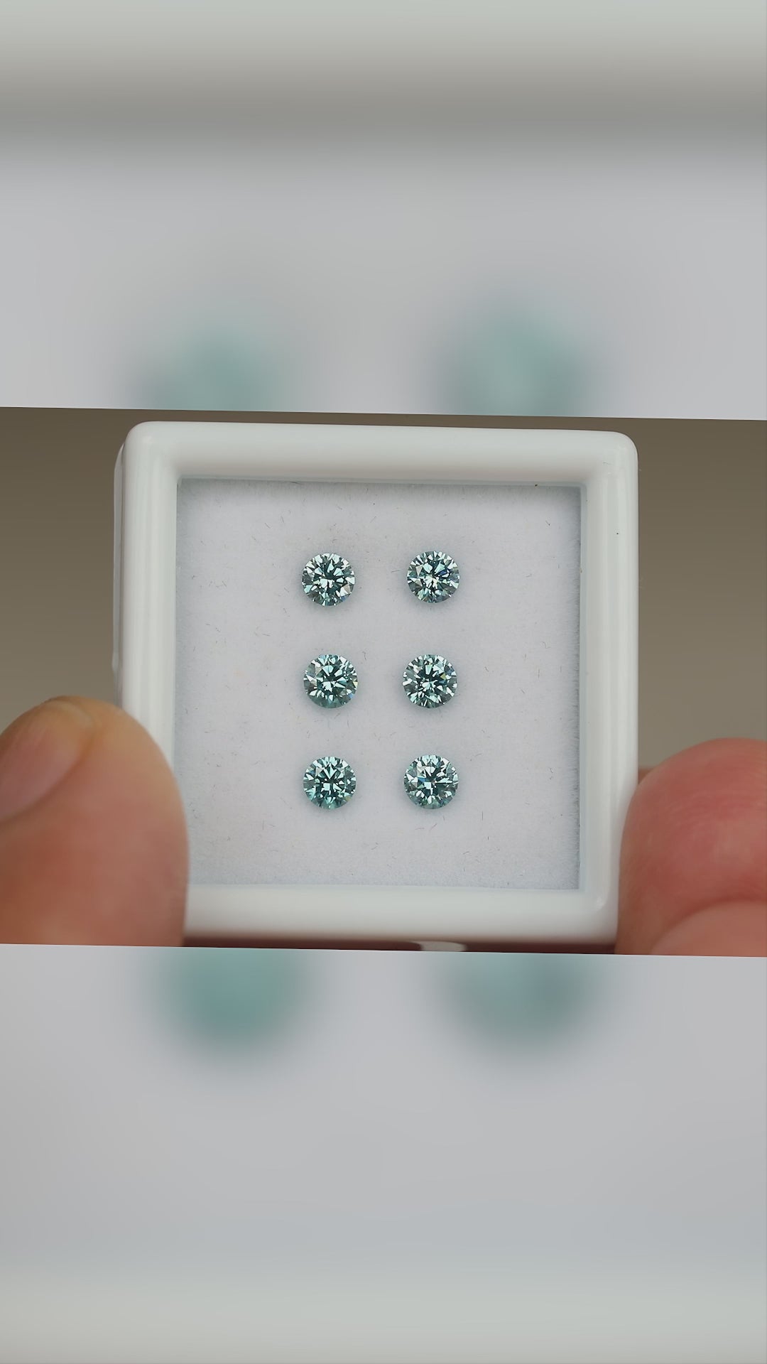 Video of six blue diamonds in a held white display box, with close face-up views and relative-scale context.