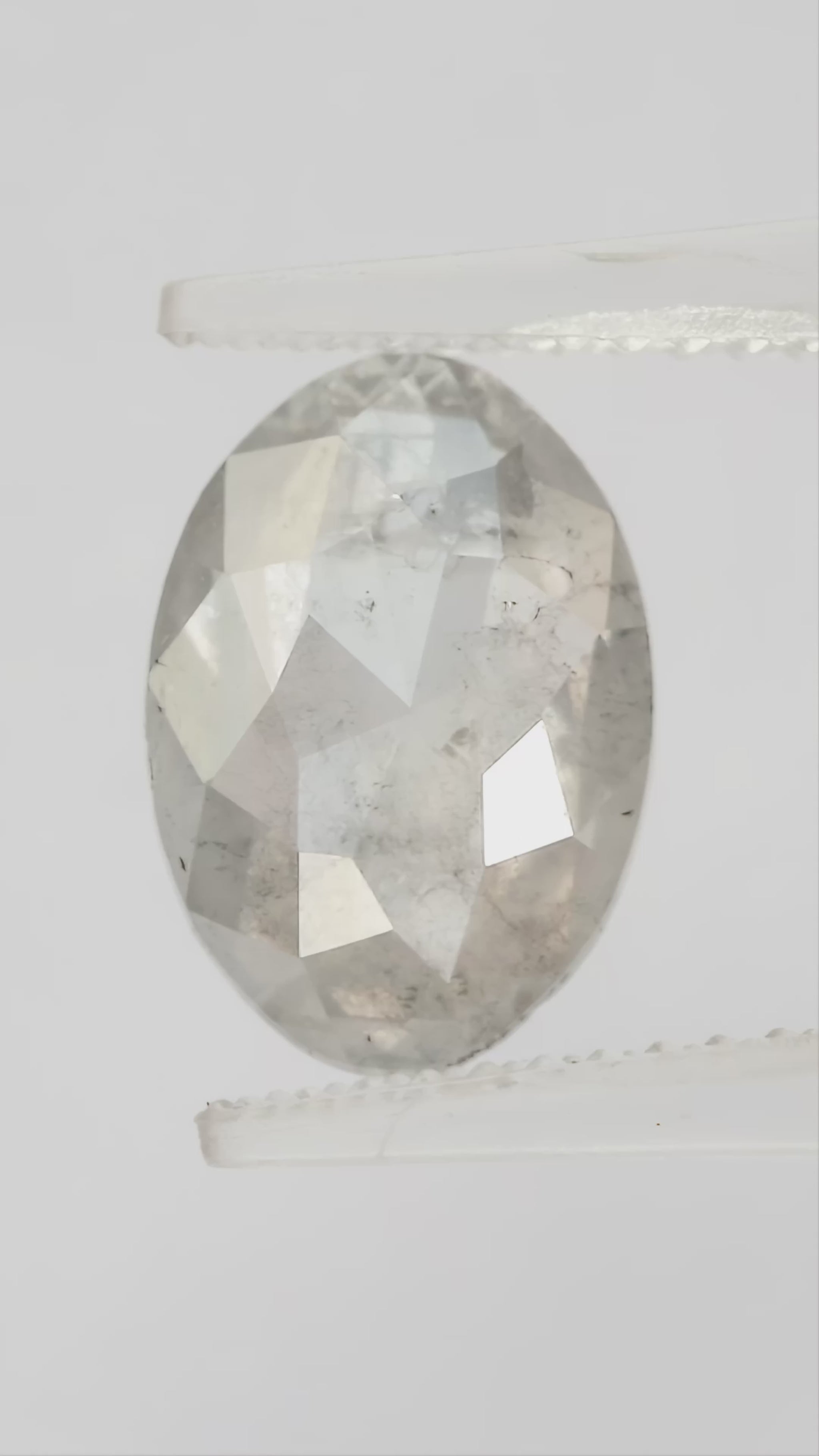 Finished video of the oval diamond rotating in pale tweezers, showing crown reflections in natural light.