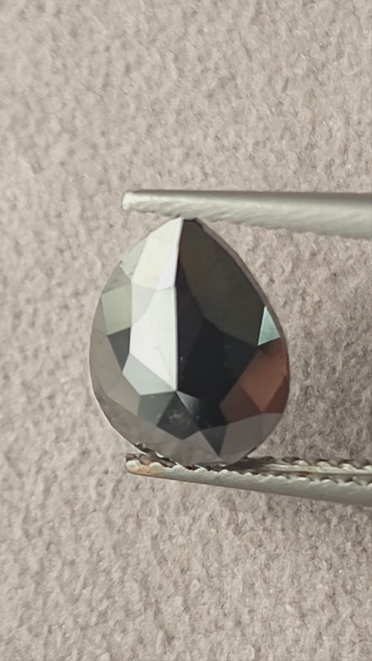 Video of the exact 1.63 carat pear rose-cut color-enhanced black natural diamond BKK-4, showing its outline and changing facet reflections as it moves.