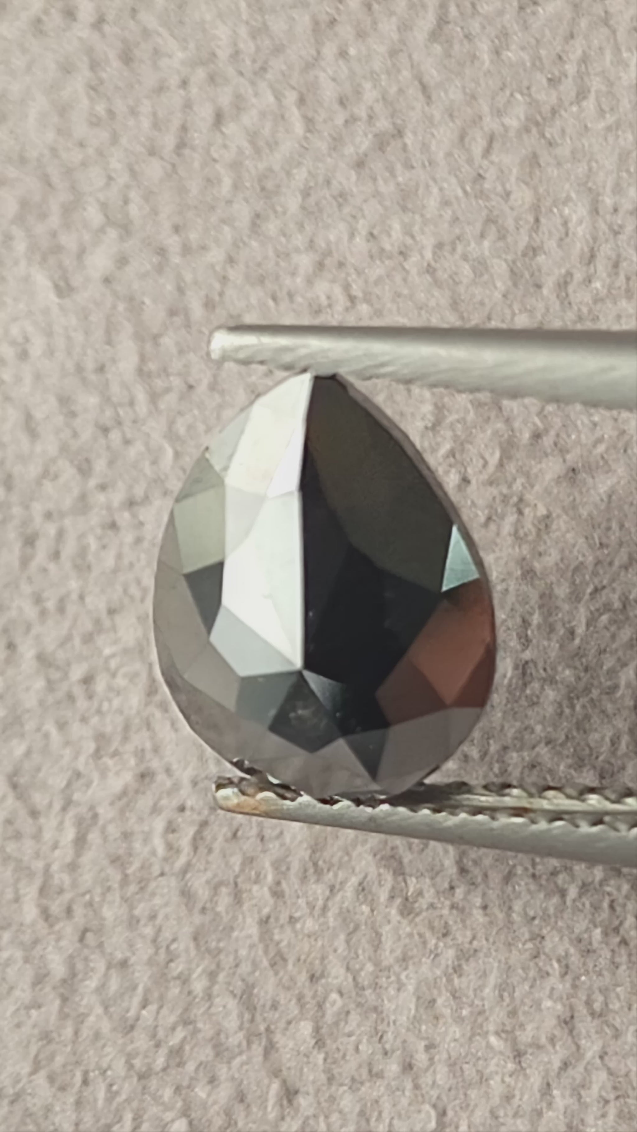 Video of the exact 1.63 carat pear rose-cut color-enhanced black natural diamond BKK-4, showing its outline and changing facet reflections as it moves.