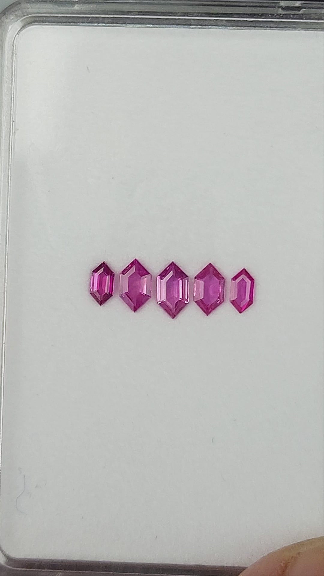 The complete five-ruby parcel shown in changing face-up and tilted tray views.