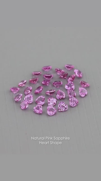 Representative parcel of pink heart-shaped sapphires viewed at changing angles on a gray surface; each purchase includes five selected sapphires.