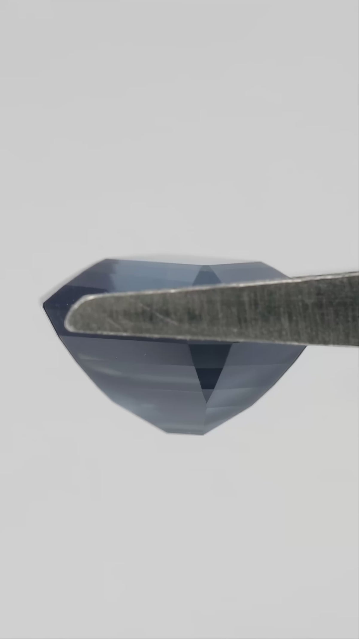 Video of the exact sapphire rotating between tweezers and on fingertips,, showing face-up color, profile, pavilion and scale.