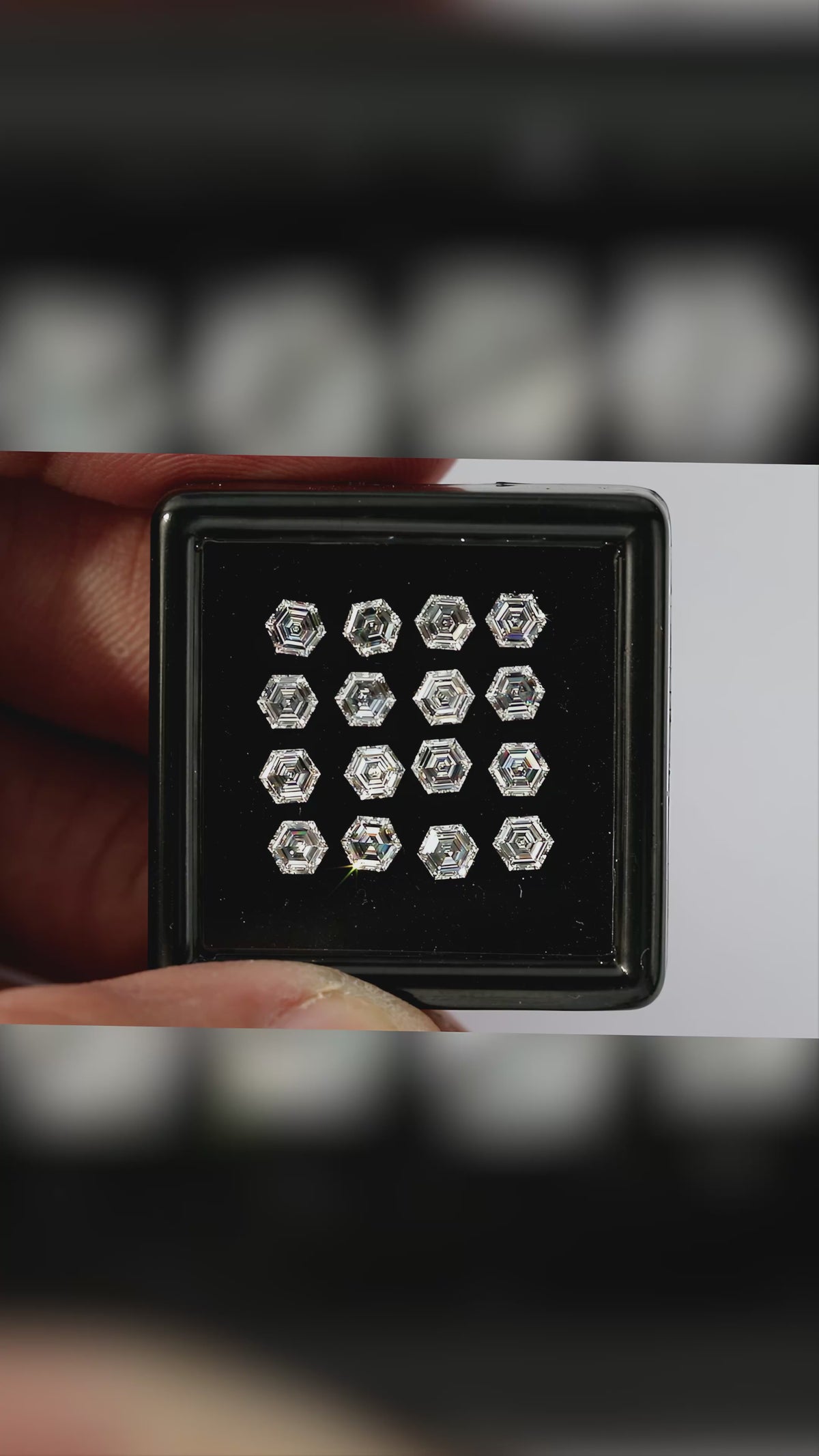 Video of hexagonal step-cut diamonds arranged face-up in a black tray held between fingers, with wider scale views and closer views of changing facet reflections.