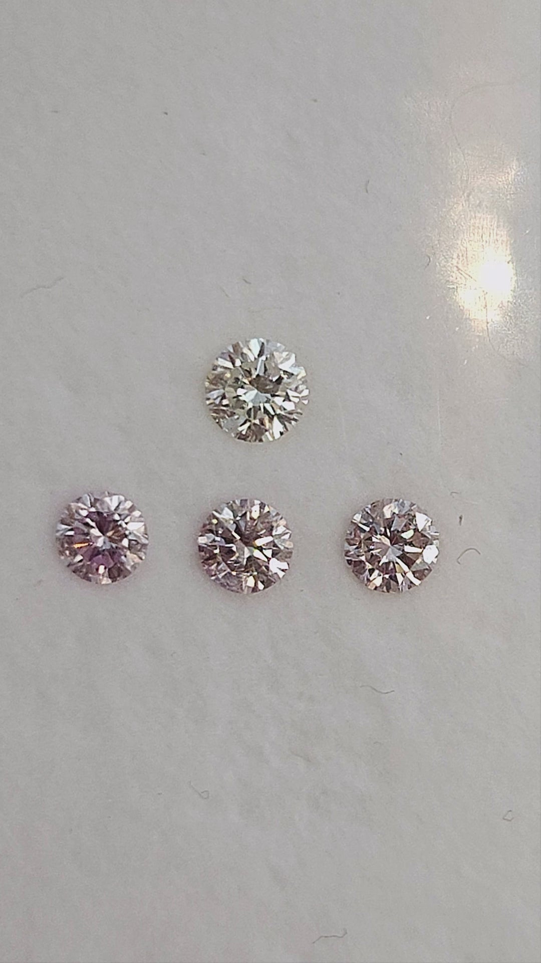 Finished natural-light video of pink round diamond samples with white color references; the group is not the purchase unit.
