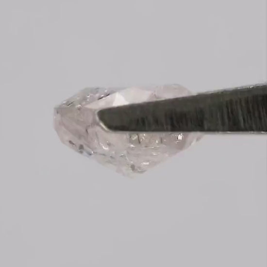 Video of the exact natural light pink cushion diamond in tweezers and on fingertips, showing facets and inclusions in motion.