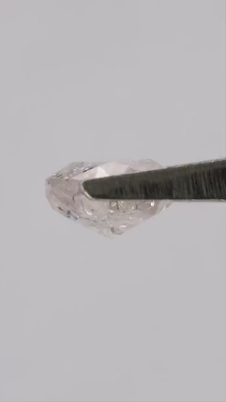 Video of the exact natural light pink cushion diamond in tweezers and on fingertips, showing facets and inclusions in motion.