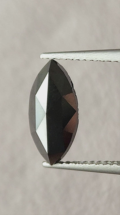 Video of the black marquise rose-cut diamond face-up in tweezers, then on a fingertip and in a palm, showing its pointed outline and changing triangular facet reflections.