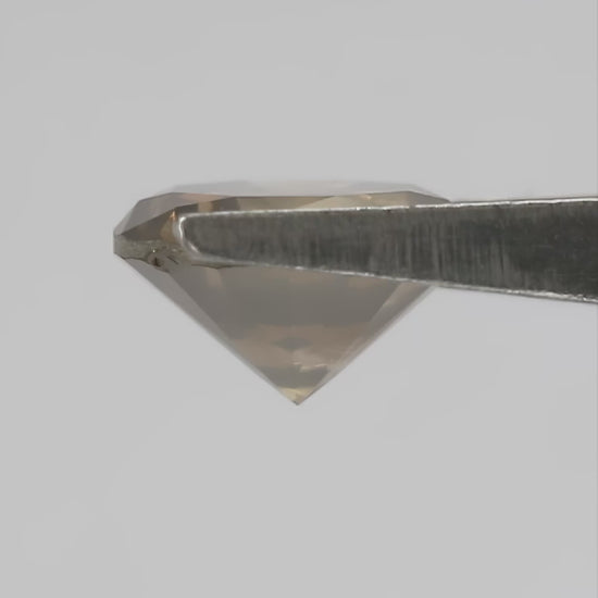 4K hand-scale video of the exact KL446 olive-brown round brilliant diamond between the fingers, showing champagne and golden reflections as it moves.