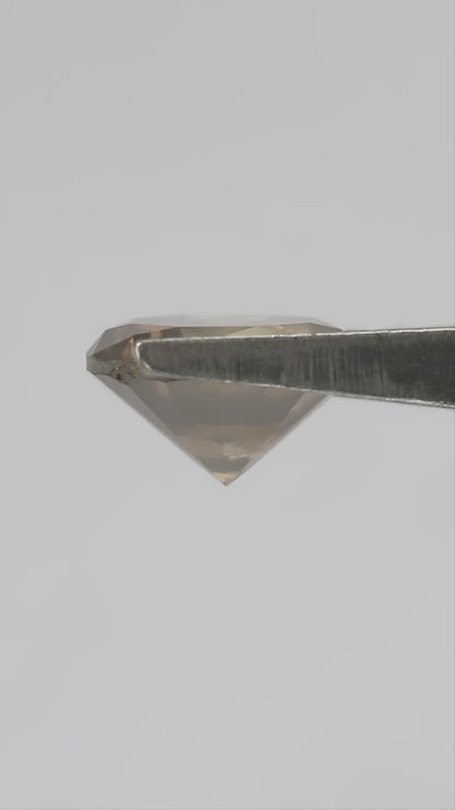 4K hand-scale video of the exact KL446 olive-brown round brilliant diamond between the fingers, showing champagne and golden reflections as it moves.