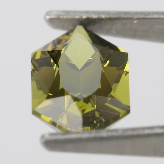 Natural-light views of the representative BLS201 olive-green lab-grown sapphire, including face-up, reverse and finger scale.